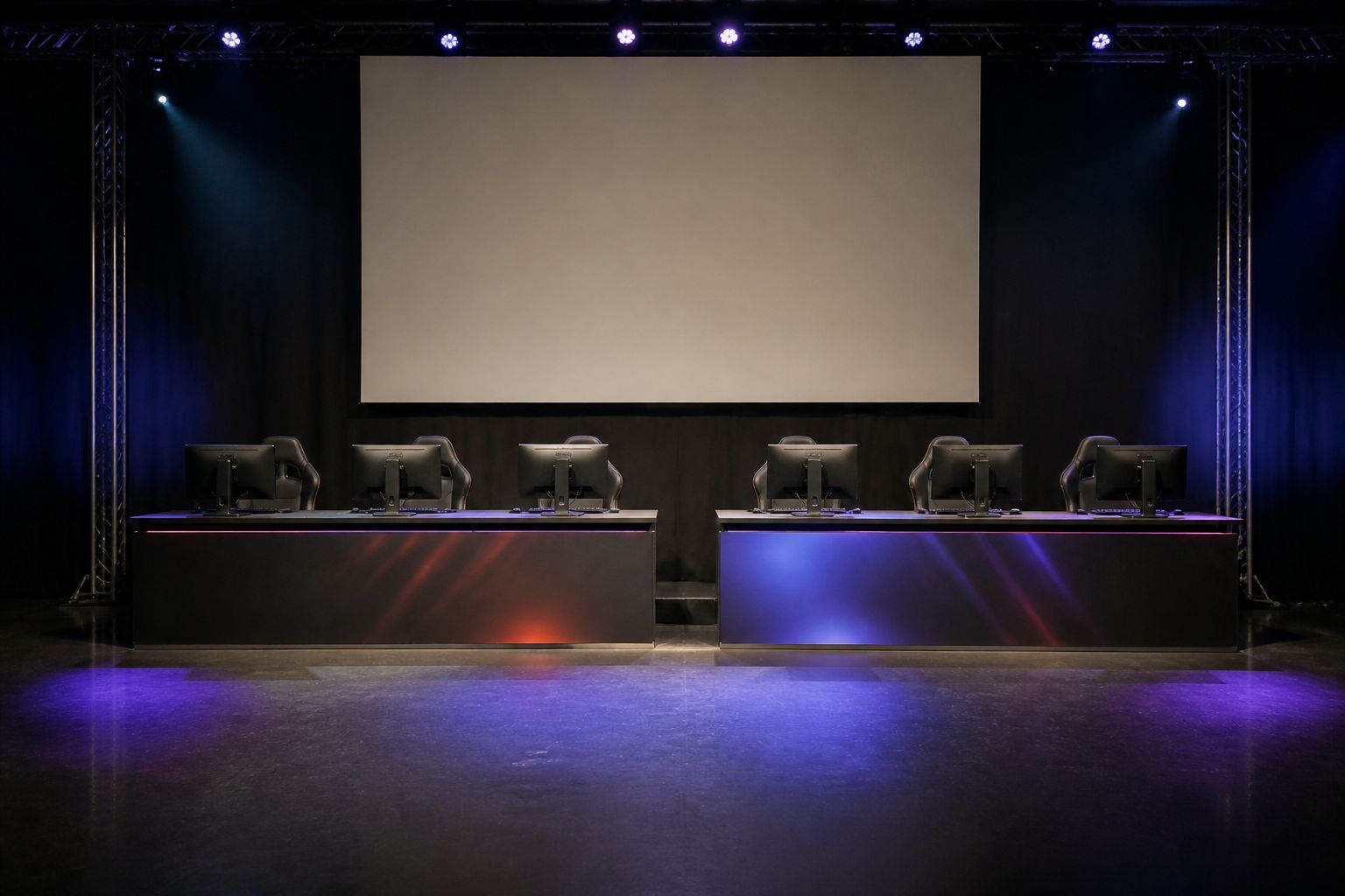 A small LAN tournament stage with a large blank screen and empty player seats